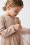 Vestido Iga beige, primer plano lateral del lacito de tul y del cuerpo de punto de manga larga