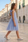 Vestido Rina azul aciano claro en una calle del casco antiguo, cuerpo entero de perfil