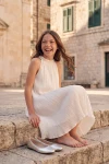 Vestido plisado Rozalia blanco al aire libre, niña sentada en una escalinata de piedra
