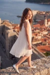 Vestido plisado Rozalia blanco sobre la muralla de la ciudad, vista lateral