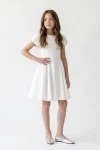 Vestido Rumi blanco con falda de vuelo, niña con la mano en la cadera, vista frontal