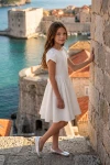 Vestido Rumi blanco con mangas tulipán al aire libre junto a un muro de piedra