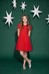 Vestido Rumi rojo sobre fondo verde con estrellas blancas, cuerpo entero