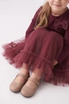 Vestido Iga burdeos con la falda de tul extendida, niña sentada