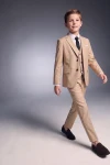 Traje Liam beige para niño con americana, chaleco, pantalón y corbata negra, en movimiento de frente