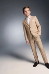 Traje Liam beige para niño, americana abrochada y mano en el bolsillo, vista de tres cuartos