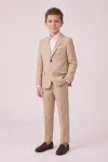 Traje Liam beige para niño con la americana abrochada y la mano en el bolsillo, cuerpo entero