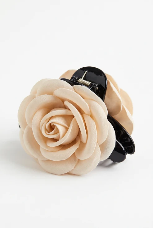 Pinza cangrejo negra con flor de tela beige, foto de producto sobre fondo blanco